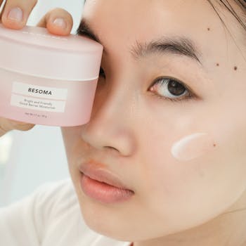 Inicio Close-up of an Asian woman holding a moisturizing cream, focusing on skincare.