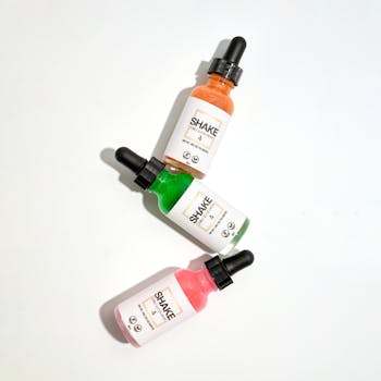 Inicio Three colorful dropper bottles arranged on a white background, ideal for product advertisements.